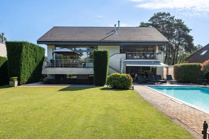 Achtergevel van Villa Grandeur met terrassen, gazon en zwembad