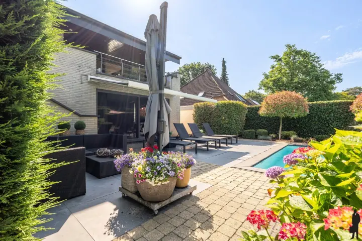 Terras met ligbedden en bloembakken bij het zwembad