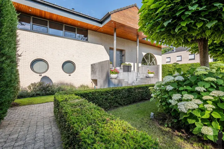Zijgevel met ronde ramen en buxushagen